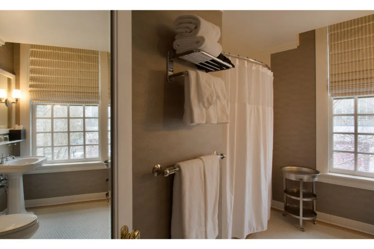 A serene bathroom scene with a window streaming in soft natural light, a fresh towel rack, and a simple shower curtain, creating a peaceful and rejuvenating atmosphere.